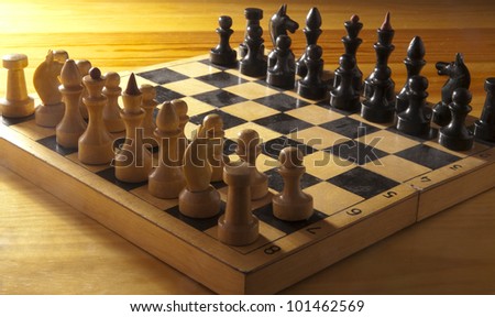 wood and plastic figures on a chess board on wooden table