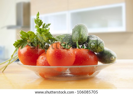 ingredients for a vegetable salad in a glass dish on a wooden table on a background of kitchen units
