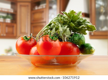 ingredients for a vegetable salad in a glass dish on a wooden table on a background of kitchen units