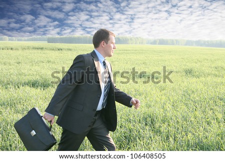 Businessman walks with suitcase in the field go to future ahead
