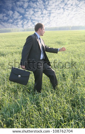 Businessman walks with suitcase in the field go to future ahead