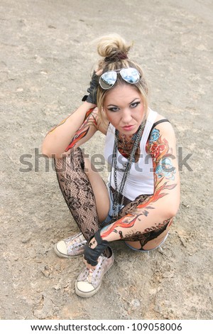 woman painted body art in the form of fire in the white  t-shirt and denim shorts and torn pantyhose on the background of desert