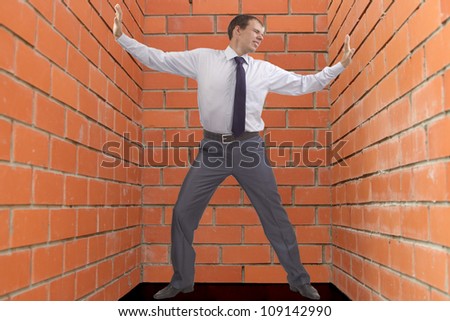 Businessman pushing an  masonry walls Man in full growth compressing it decompresses the brick walls