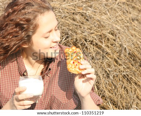 Redhead girl is sitting based on the straw drinking kefir and eating foliation muffin with jam