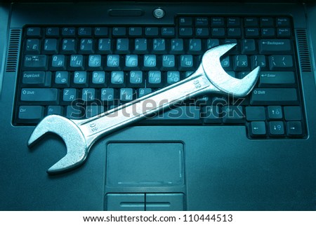 black blue laptop with a spanner on the keyboard
