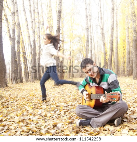 guy playing on guitar and the girl is dancing