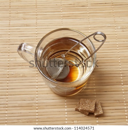 Tea in a transparent mug with sugar on bamboo background