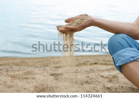 time is money  hand pours the sand Hand is pouring coral sand on a beach