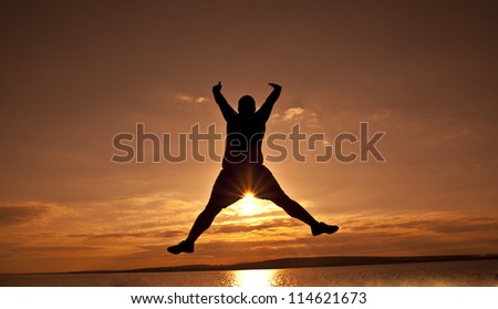 black silhouette of man in happy jump on orange sunset sky and sea