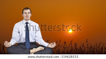 businessman sitting on filed in lotus pose, sunset time