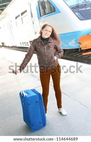 Beautiful young woman with luggage is waiting a train