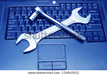 blue laptop with a spanner on the keyboard