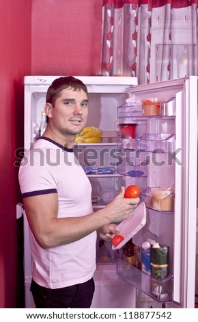 Portrait of young man looking at different healthy food inside r