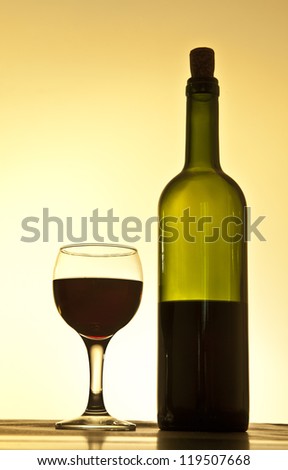 Elegant red wine glass and a wine bottle in yellow  gradient background