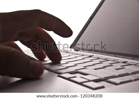 Silhouetted image someone typing on laptop computer Symbol  shadow economy illegal operations cracking computer passwords fraud hacking advertising sales illegal non payment  taxes concealment income