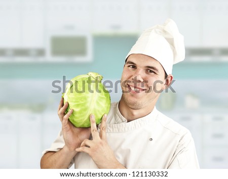 attractive cook with fresh cabbage on blue kitchen set  background
