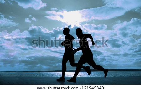Female and male - paar -  runner full length silhouette against the blue sky and sun