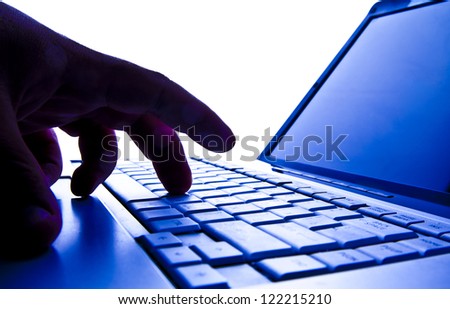 Silhouetted image someone typing on laptop computer Symbol shadow economy illegal operations cracking computer passwords fraud hacking advertising sales illegal non payment taxes concealment income