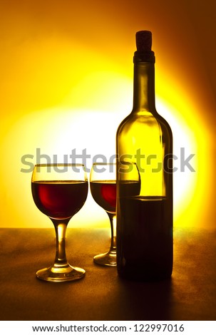 two Elegant red wine glass and a wine bottle in yellow gradient background