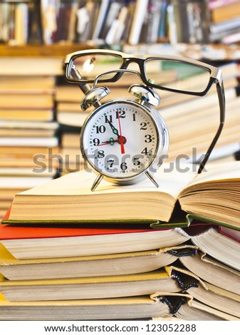 Clock, glasses, book on bookshalf  background - The idea of ??hard training, eye damage and vision of prolonged read, the need of Learning in a short time