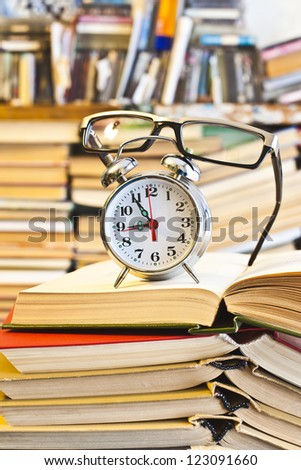 Clock, glasses, book on bookshalf  background - The idea of ??hard training, eye damage and vision of prolonged read, the need of Learning in a short time