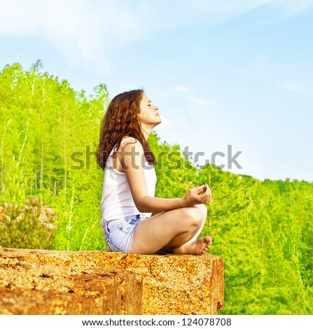Beautiful woman meditating on a peak rock and meditating