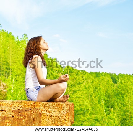 Beautiful woman meditating on a peak rock and meditating