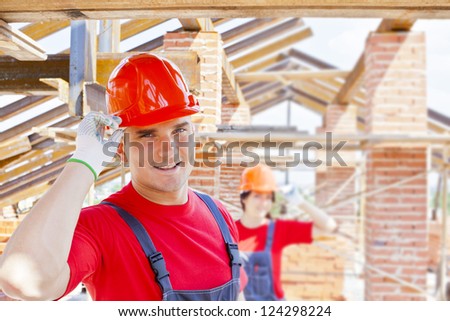 working couple - woman and man - two Young builders on a background of metal roof trusses