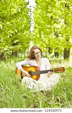 Teenager girl with guitar against green grass   Space for inscription