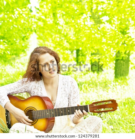 Teenager girl with guitar against green grass   Space for inscription