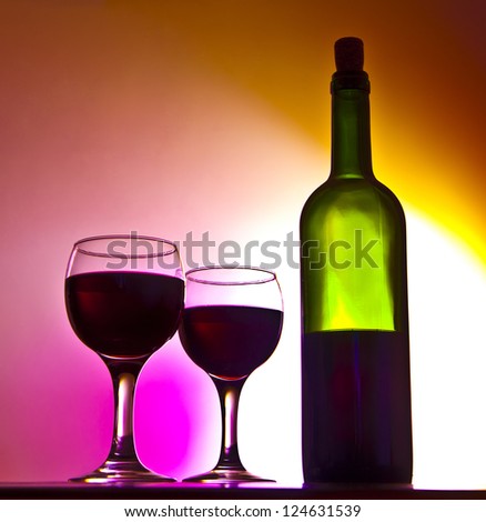 two Elegant red wine glass and a wine bottle in yellow gradient background