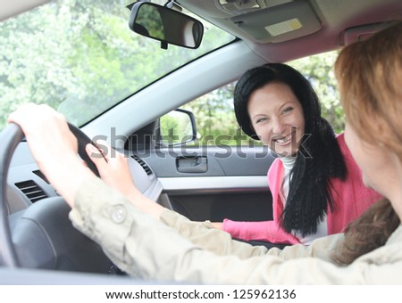 View through past the female driver to an attractive woman passenger in a motor car with focus to the passenger
