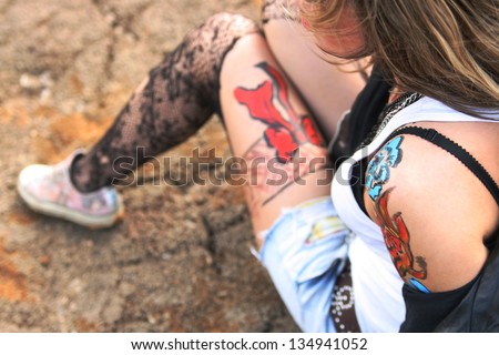 woman painted body art in the form of fire in the white t-shirt and denim shorts and torn pantyhose on the background of desert