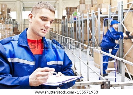 warehouse worker in a special uniform is recording and accounting of the contents in cardboard boxes in stock