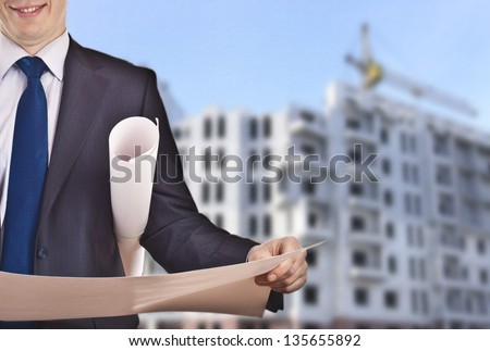 View Of Architect Looking Comparing Housing Project On Being Built Multistory Apartment Background