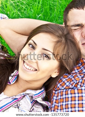 A portrait of a sweet couple in love lying on green fresh grass
