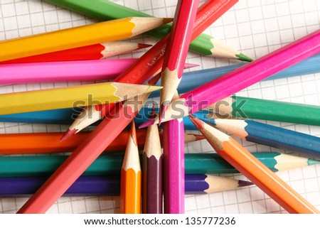 Pencils in mess on checkered notebook sheet