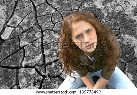 Young ginger woman alone in the darkness on dry craced desert   view from the top