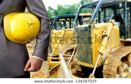 engineer yellow helmet for workers security over yellow tractors with backhoe