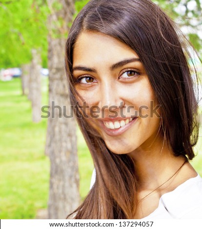 Summer / spring woman smiling happy sitting in white dress in sunny park. Beautiful mixed ethnic Caucasian / Asian girl outdoor.
