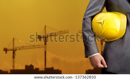 engineer yellow helmet for workers security on the background of a new high-rise apartment buildings and construction cranes and evening sunset sky