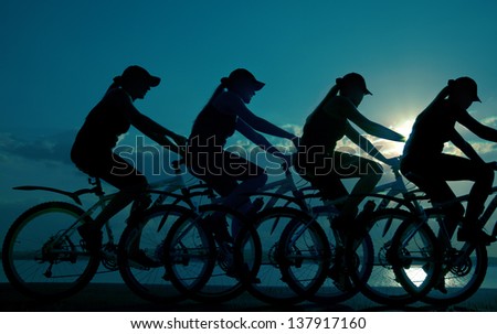 Image of sporty company friends on bicycles outdoors against sunset. Silhouette The four phases of motion of a single cyclist along the shoreline coast