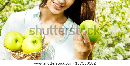 Portrait half of face young beautiful woman  holding an apple, on Spring blooming apple tree background summer nature.