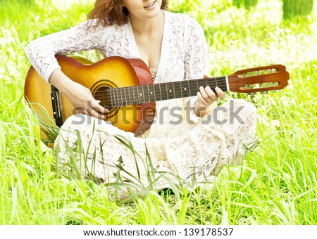 Teenager girl with guitar against green grass Space for inscription  No face