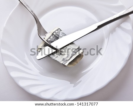 Big bucks/ One hundred american dollars bill on a white plate, with fork and knife. Buying power, money management, charity events & other in business, economy, finance, banking and everyday life.