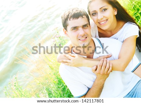 love latin hispanic guy with the girl in striped shirts and blue jeans sitting on green grass beach
