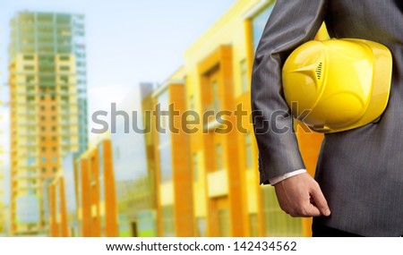 Engineer Yellow Helmet For Workers Security On The Background Of A New High-Rise Apartment Buildings Evening Sunset Sky