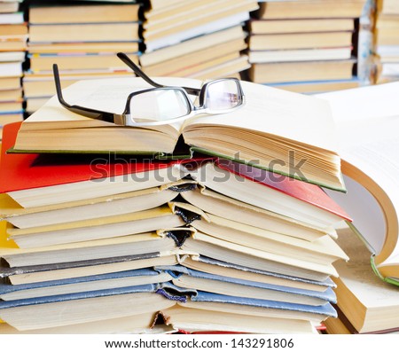 Copy Space for inscription opened books and glasses on table front of a full bookshelf