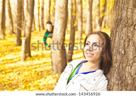 A picture of a young couple standing in the park and and play hide and seek