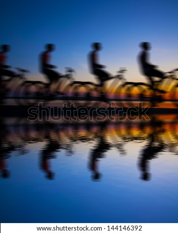 Image of sporty company friends on bicycles outdoors against sunset. Silhouette A lot phases of motion of a single cyclist along the shoreline coast Reflection on water Space for inscription